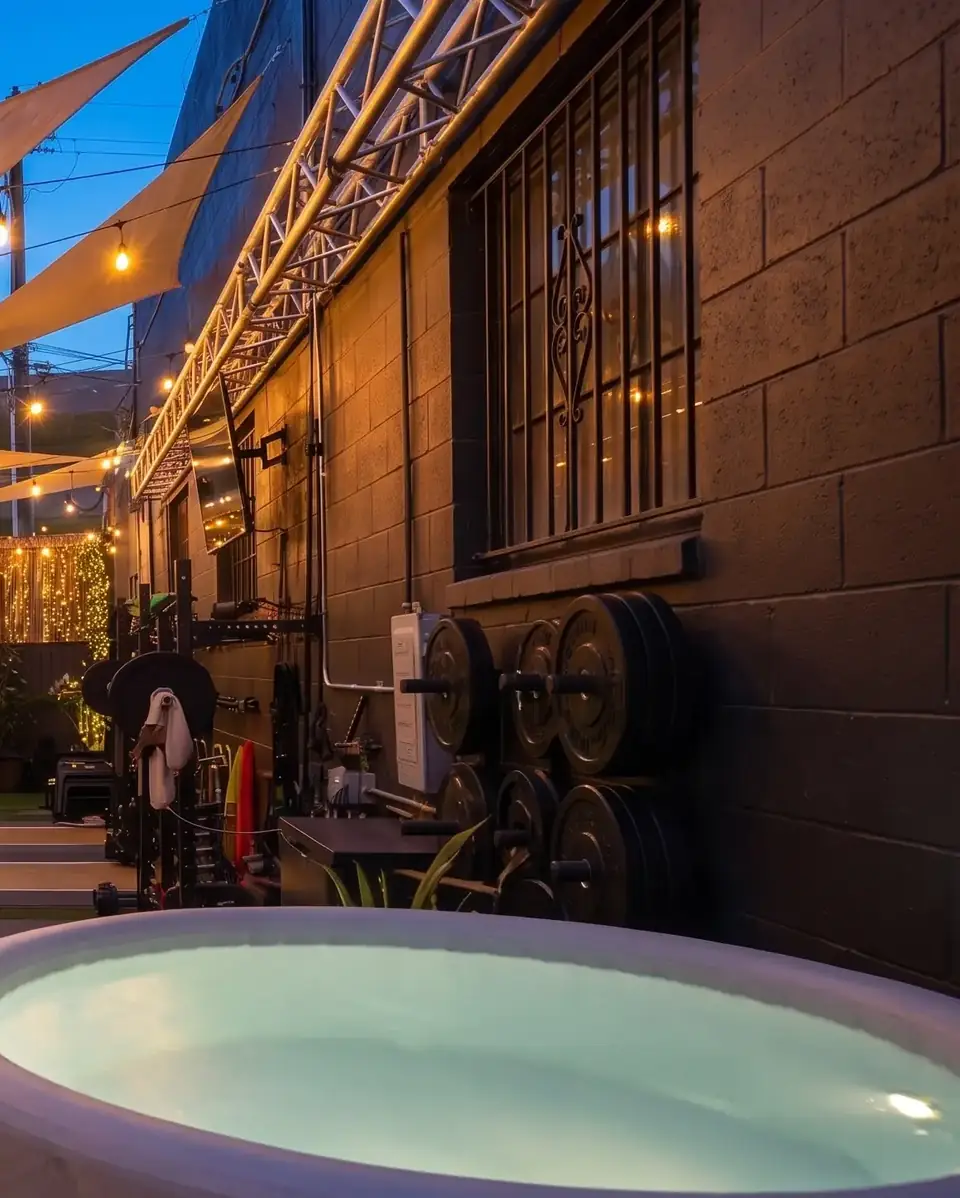 The outdoor gym at dusk with racks, plates and the cold plunge