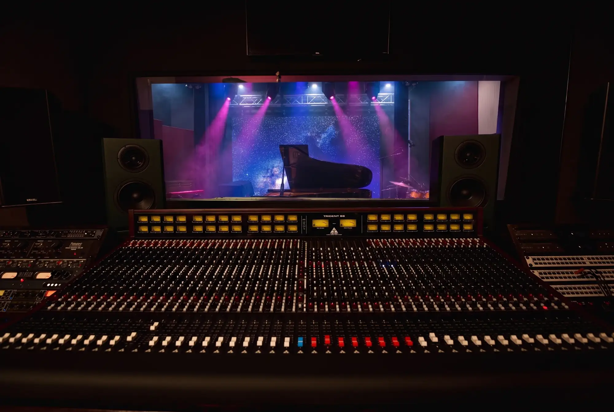 The Trident 88 console behind glass, looking onto the Live Room stage and a grand piano under stage lights