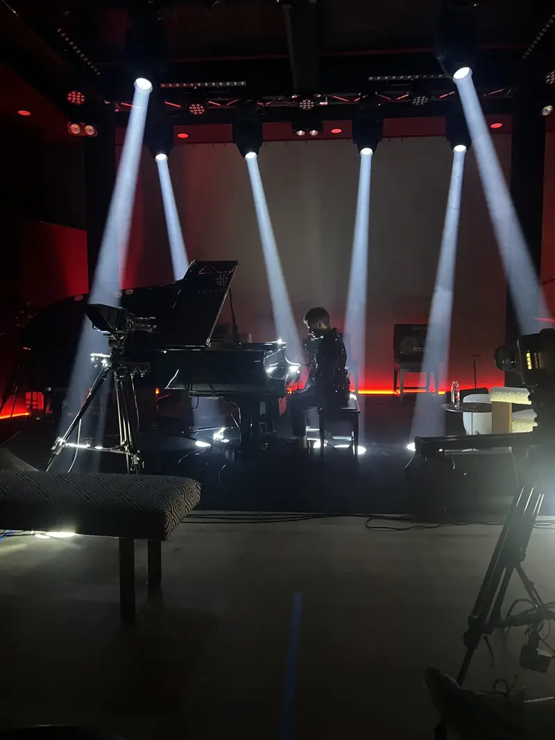The Live Room stage with light beams over a grand piano